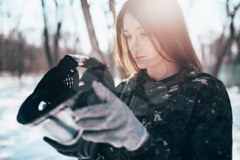 Female paintball player puts on protection mask, winter forest battle. Extreme sport, game equipment