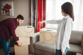 Happy couple arrange cardboard boxes on a room, moving to new house. Relocation to apartment with packaging