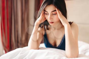 Unhappy woman in depression sits in bed under the blanket, female stress concept. Emotional stressed girl having a problem
