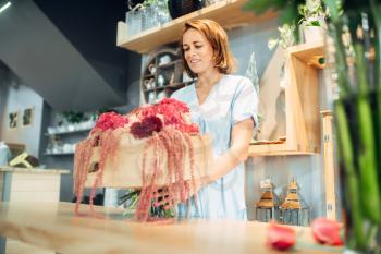 Female florist puts fresh flowers in a vase in floral shop. Floristry service, floristic business