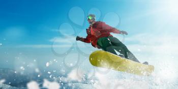 Snowboarder in glasses makes a jump, sportsman in action. Winter active sport, extreme lifestyle. Snowboarding in mountains, blue sky on background