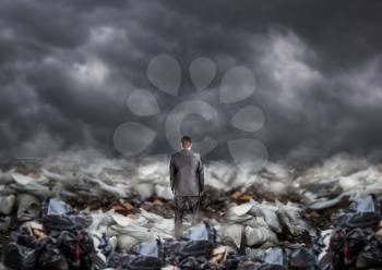 Businessman standing in the middle of a landfill, back view, piles of garbage. Environmental business and ecology pollution problem