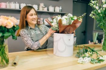 Florist in apron accepts payment from female customer in flower boutique. Floral shop business concept