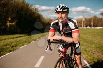 Cyclist in helmet and sportswear, cycling training on asphalt road. Male sportsman rides on bicycle. Workout on bike path