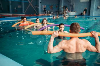 Instructor and female group on workout in swimming pool. Aqua aerobics training, water sport 