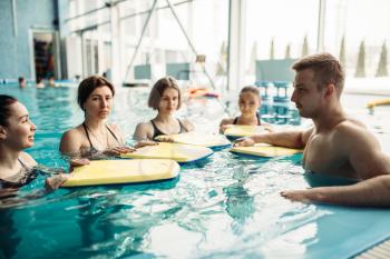 Male trainer swims with female class on aqua aerobics workout in swimming pool. Water sport