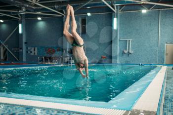 Swimmer in goggles jumping from the tower into the water, training in swimming pool, healthy activity. Underwater sport