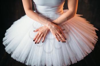 Classical ballet dancer body in white dress and cross hands, black background. Elegance ballerina poses