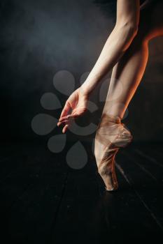 Ballerina hand and legs in pointes, black wooden floor. Ballerina in red dress and black practice dancing on the stage in theatre
