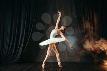 Graceful ballerina in white dress dancing in class. Ballet dancer training on the stage