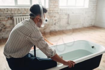 Funny businessman in swimming mask sitting on the edge of the bathtub. Business fortune concept