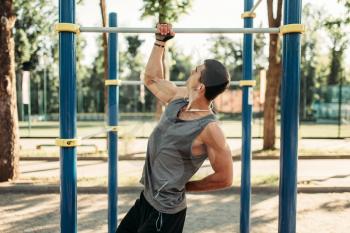 Athletic man pulled up on one hand, exercise on horizontal bar, outdoor fitness workout. Muscular sportsman on sport training in park