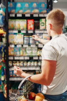 Male customer with basket choosing personal hygiene products in market. Shopping in supermarket