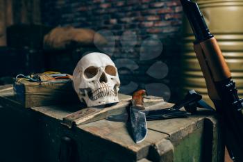 Human skull, bomb, knife and kalashnikov rifle on box of ammunition, nobody. Terrorism and terror horror concept