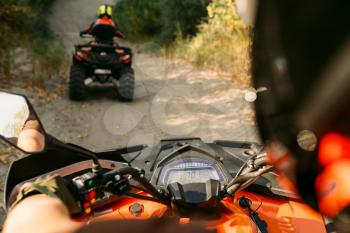 Atv riding in action, view through the eyes of the driver. Two riders on quad bikes having offroad adventure in forest