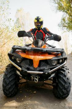 Rider in helmet and equipment on quad bike, front view, closeup. Male quadbike driver, atv riding