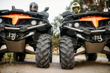 Two riders in helmets and equipment on quad bikes, front view, closeup. Male quadbike drivers, atv riding, extreme sport