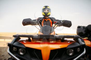 Rider in helmet and equipment on quad bike, front view, closeup. Male quadbike driver, atv riding