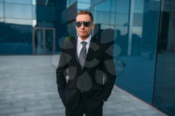 Male bodyguard in suit and sunglasses outdoors. Guarding is a risky profession. Professional guard, politician persons and businesspeople safeguard, safe control