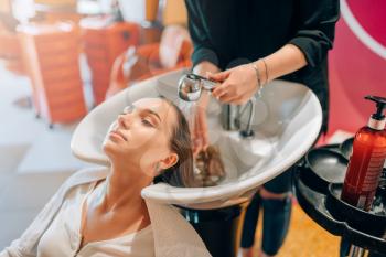 Hairdresser washes customer hair in basin, hairdressing salon. Professional haircutting in beauty studio