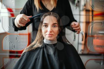 Woman in hairdressing salon, female stylist with scissors and comb in hands on background. Hairstyle making in beauty studio