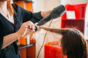 Stylist drying hair with a dryer, female hairdress in hairdressing salon. Hairstyle making in beauty studio