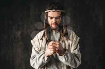 Man in the image of Jesus Christ praying, dark background. Belief in god, christian faith