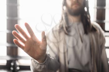 Jesus Christ in white robe reaching out his hand, window with sunlight on background, peace symbol. Son of God, christian faith
