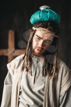 Man in the image of Jesus Christ with a heating pad on his head, crucifixion cross on black background