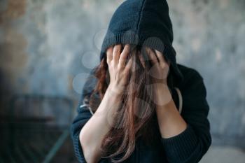 Female in a hoodie holds her head. Drug addiction concept, addicted people