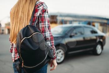 Young woman driver with travel bag against a car. Female person and vehicle, automobile driving concept