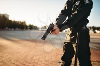 Male cop in uniform with gun in hands. Police officer with weapon. Law protection concept, safety control job