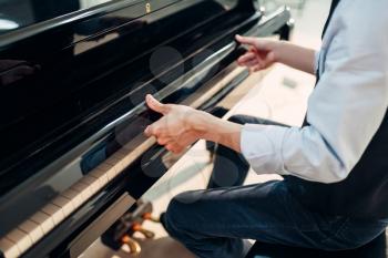 Male pianist opens the keyboard lid of the black grand piano. Musician prepares to performance on the royale, classical musical instrument