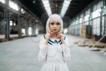 Anime girl, blonde woman with makeup. Cosplay, japanese culture, doll in dress on abandoned factory