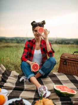 Young woman sitting on plaid, picnic in summer field. Romantic junket, happy holiday
