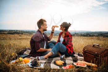 Happy love couple on picnic in summer field. Romantic junket of man and woman