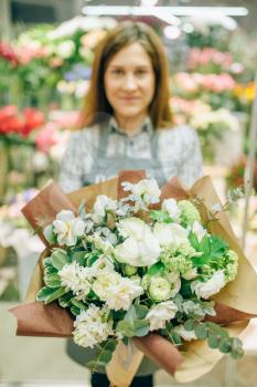 Female florist in apron with fresh bouquet in flower shop, floral business concept