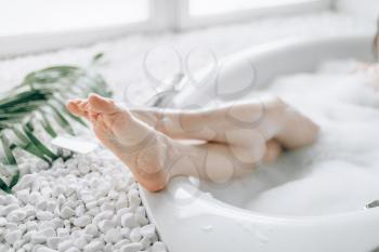 Female person heels sticking out of the bath with foam. Relaxation, health and body care in bathroom, spa