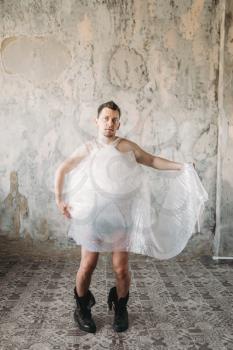 Naked freak man wrapped in packaging film wearing shoes without laces, grunge room interior. Crazy male person in abandoned house
