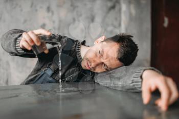 Autistic man pours water from the glass on the table. Alone guy in abandoned house, autism syndrome