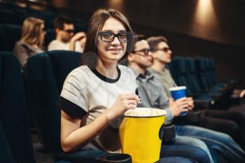 Young woman in 3d glasses with popcorn sitting on seat in cinema. Showtime, movie watching 