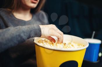 Young woman eats popcorn while watching movie in cinema. Showtime