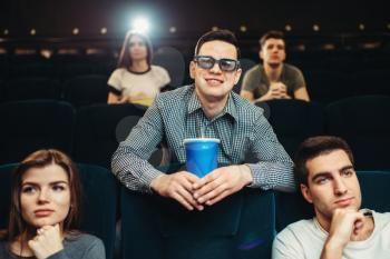 Young smiling man in 3d glasses holds beverage and poses in cinema. Showtime, entertainment industry, movie watching