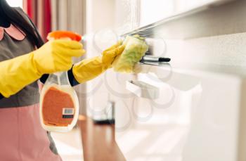 Housemaid hands in gloves cleans furniture with a cleaning spray, hotel room interior on background. Professional housekeeping, charwoman