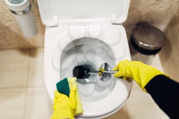 Housemaid hands in rubber gloves cleans the toilet with brush, hotel restroom interior on background. Professional housekeeping service, charwoman, sanitary processing