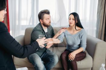 Husband soothes wife at psychotherapist reception. Female doctor helps patients with consultation, family psychology support