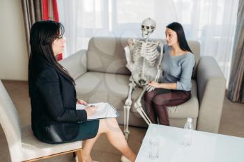 Young woman with human skeleton at psychologist reception. Female doctor helps patients with consultation, family psychology support