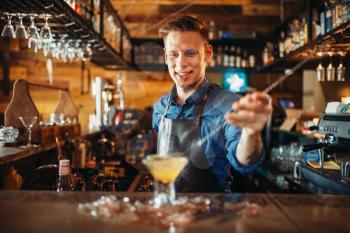 Male bartender prepares alcoholic coctail with ice. Barkeeper occupation, barman at the bar counter