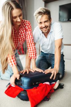 Couple packing their bag for vacation, bag overflowing. Fees on journey concept. Luggage preparation