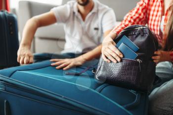 Couple packing their suitcases for vacation and take documents with them. Fees on journey concept. Luggage preparation
